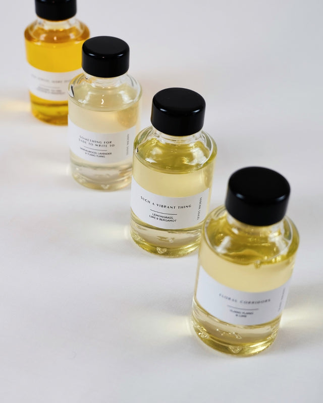 Close-up view of hand-blended mini essential oil reed diffusers showcasing natural amber gradient tones.