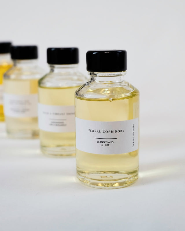 Four studio-size 50ml diffuser vessels arranged on a stark white background next to a raw cotton pouch.