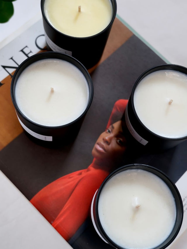 Four hand poured aromatherapy candles with natural essential oils, displayed on a magazine next to a picture of a woman.