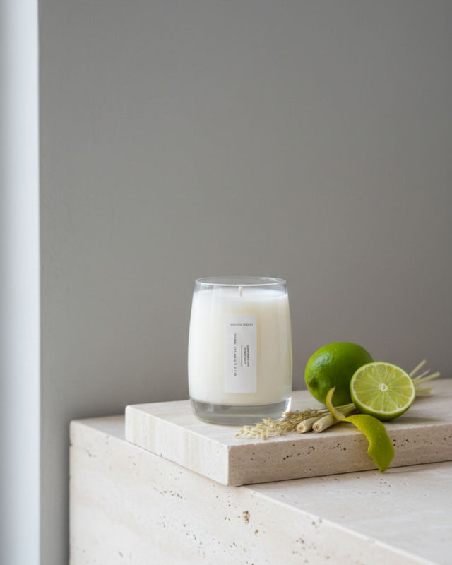 Minimalist "Such A Vibrant Thing" candle by Mayowa Samuel, displayed on a stone ledge with fresh lime and lemongrass. A luxury soy candle scented with lemongrass, lime, and bergamot