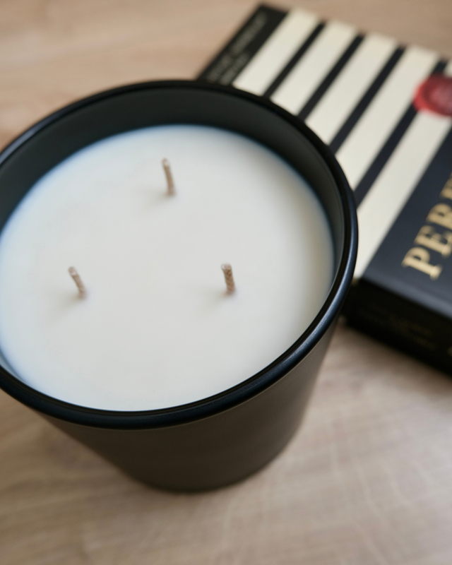 Close-up angle of MAYOWA SAMUEL 650g three-wick luxury scented candle in matte black vessel on light wood